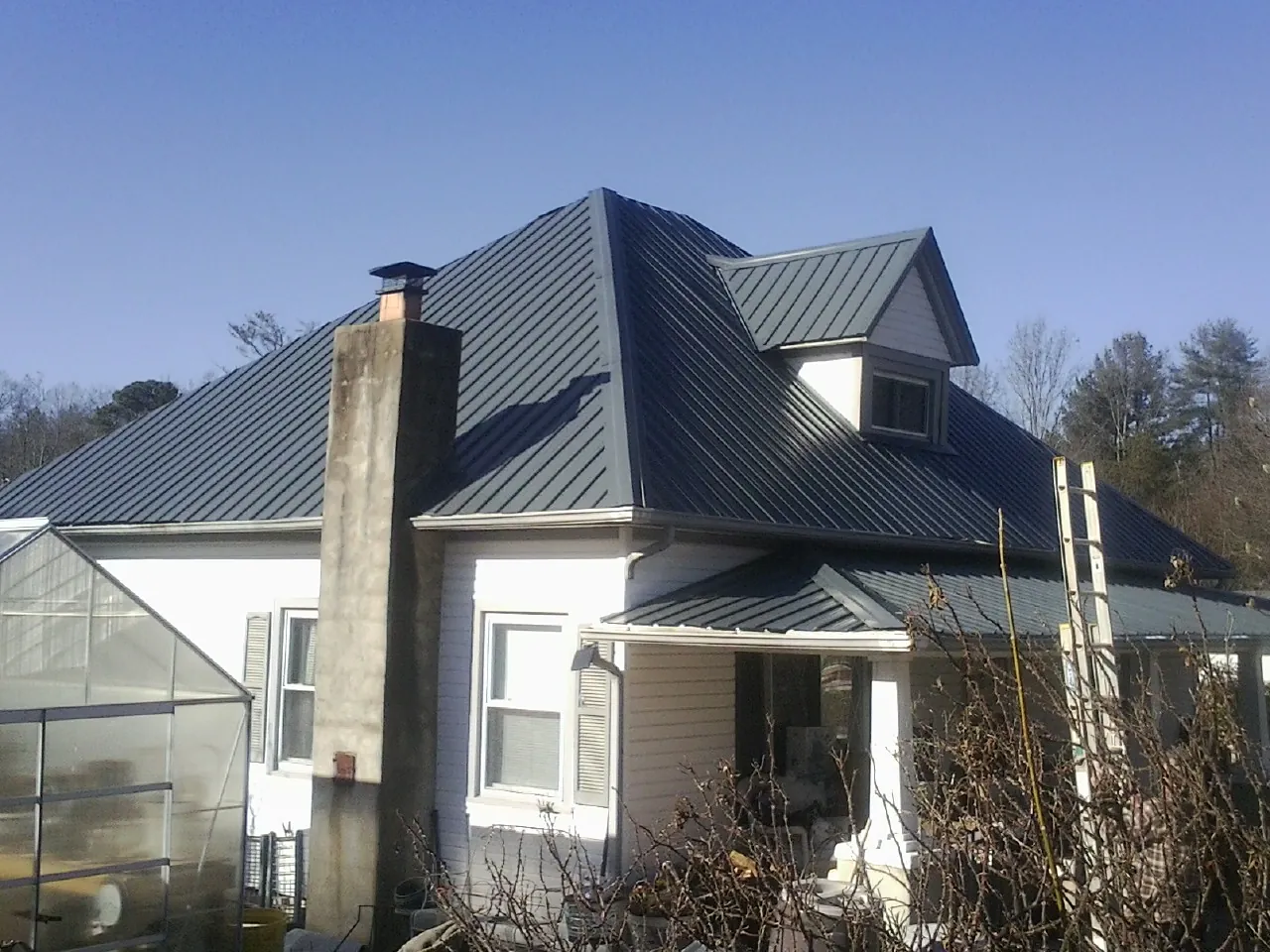 Dark blue standing seam metal roof on a white farmhouse with dormer — Slate & Tile Roof Repair by Roofing Brothers in Cuddebackville