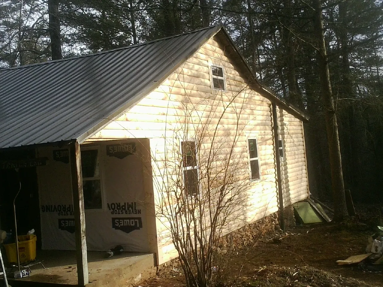 Log siding gable end under a dark metal roof edge in Cuddebackville