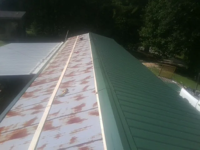 Old rusted panels beside newly installed green metal roofing — Wind Damage Roof Repair by Roofing Brothers in Cuddebackville