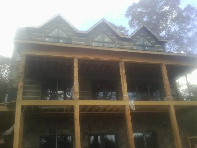 Dormers and porch framing on a large log home under construction — Roof Coating work by our crew in Cuddebackville