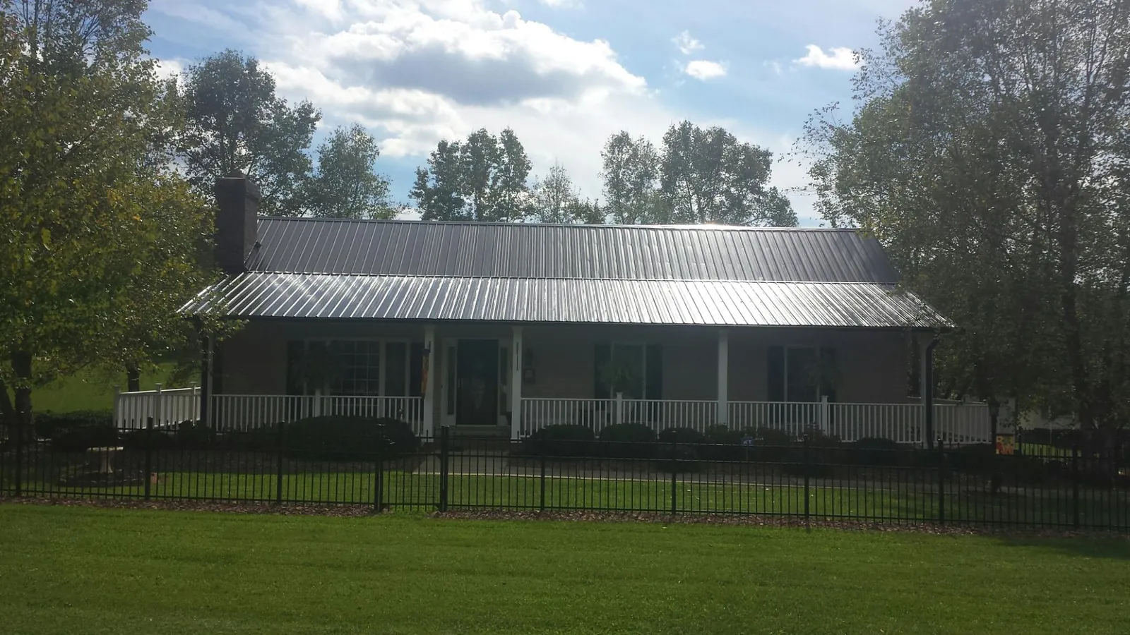 Gray metal roof on a brick ranch with a full width front porch — Gutter Guard Installation work by our crew in Cuddebackville