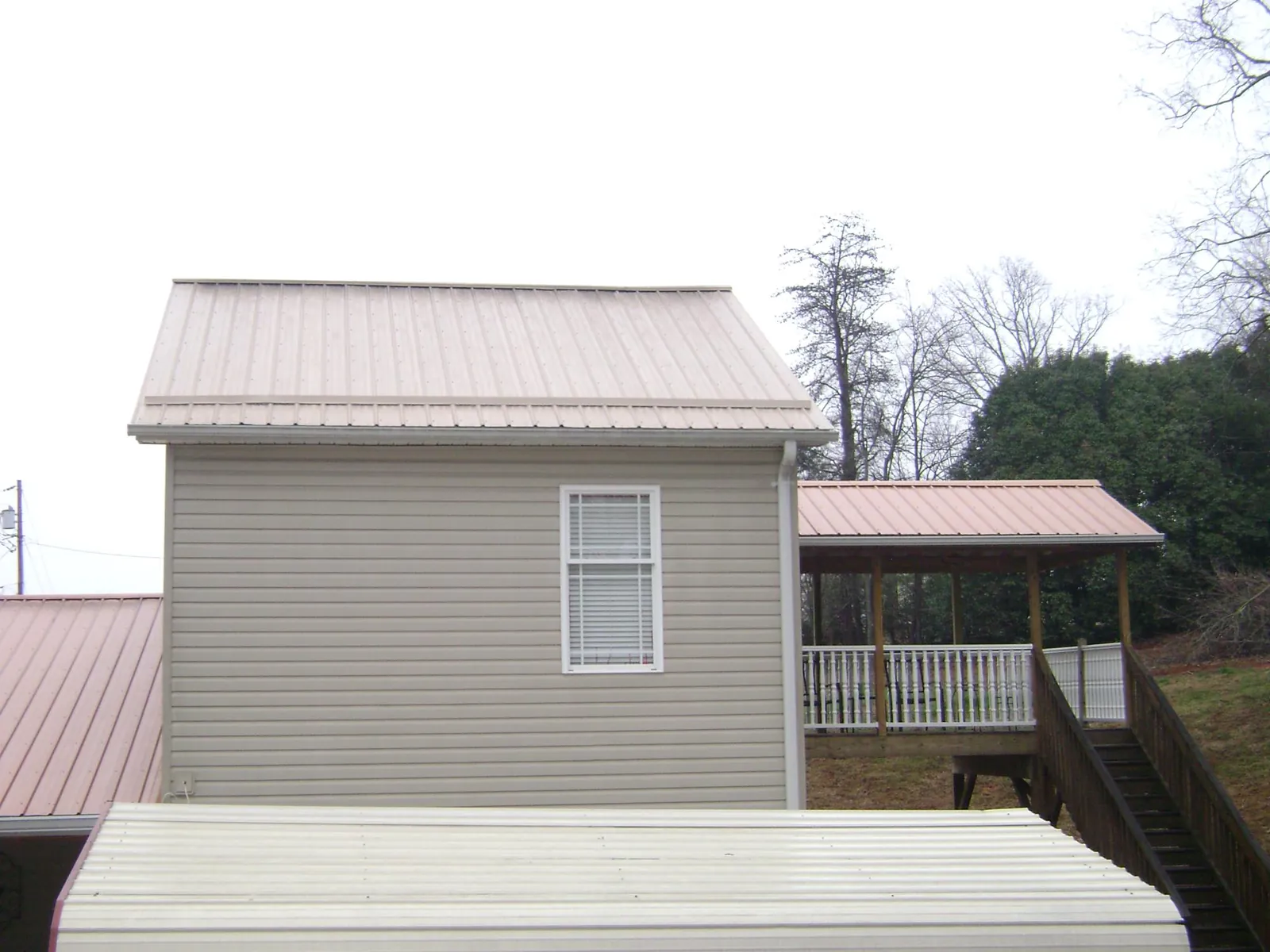 Tan metal roofs on a two story addition and attached porch, from a Roof Replacement job in Cuddebackville