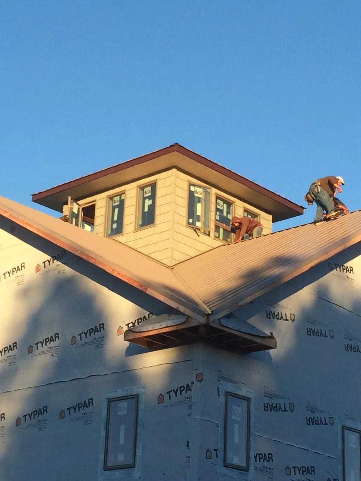 Roofers working around a rooftop cupola on a new metal roof at sunset — Roof Waterproofing in Cuddebackville by Roofing Brothers